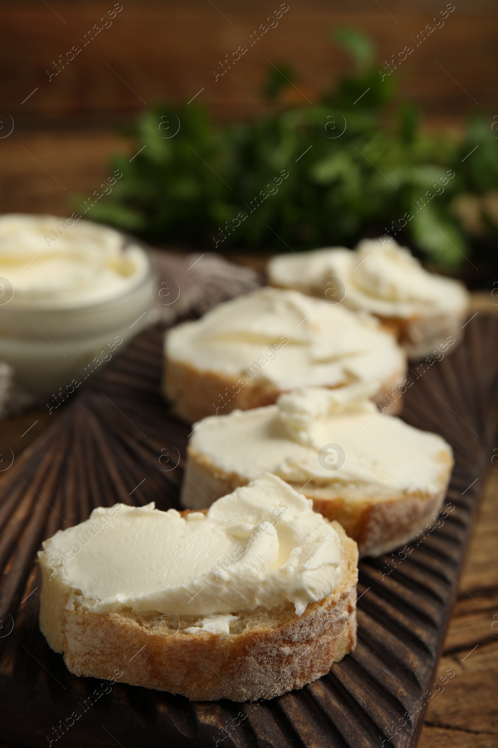 Photo of Bread with cream cheese on wooden board, closeup