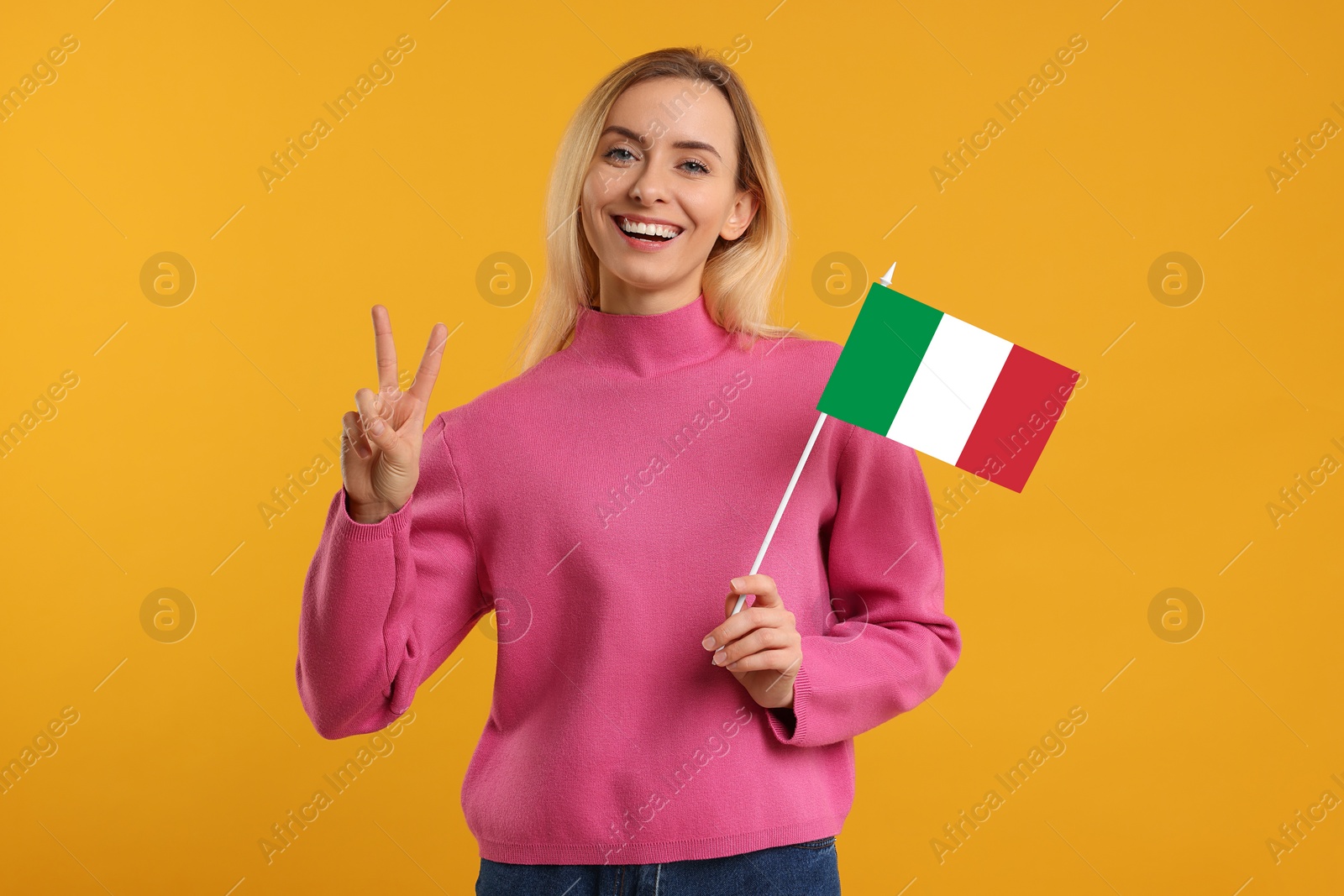 Image of Happy young woman with flag of Italy showing V-sign on yellow background