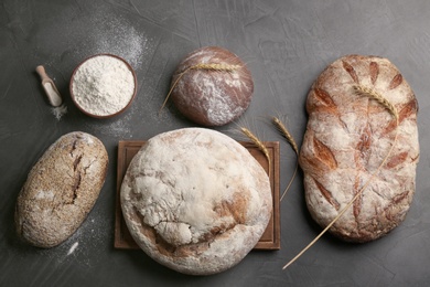 Photo of Different kinds of fresh bread on grey table, flat lay