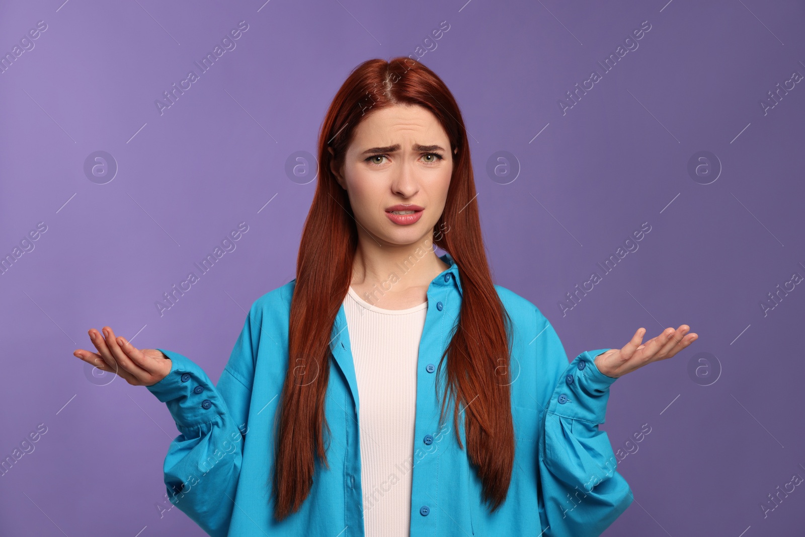 Photo of Confused woman with red dyed hair on purple background