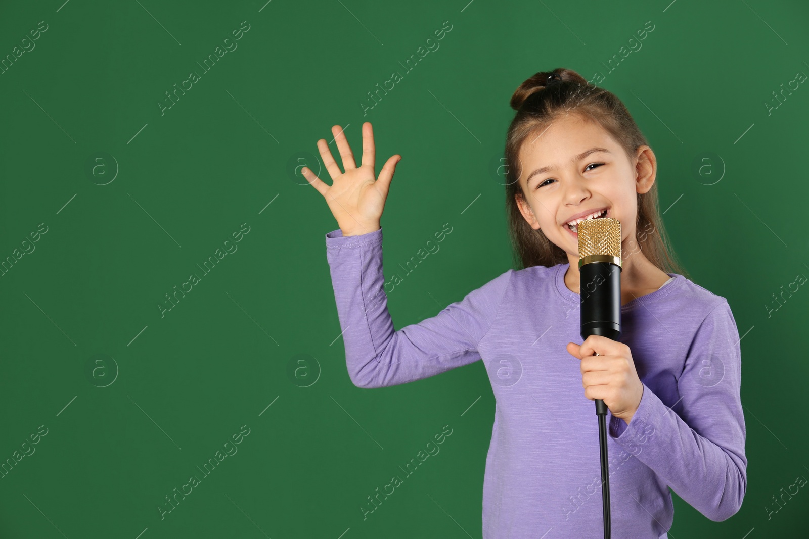 Photo of Cute funny girl with microphone on color background. Space for text