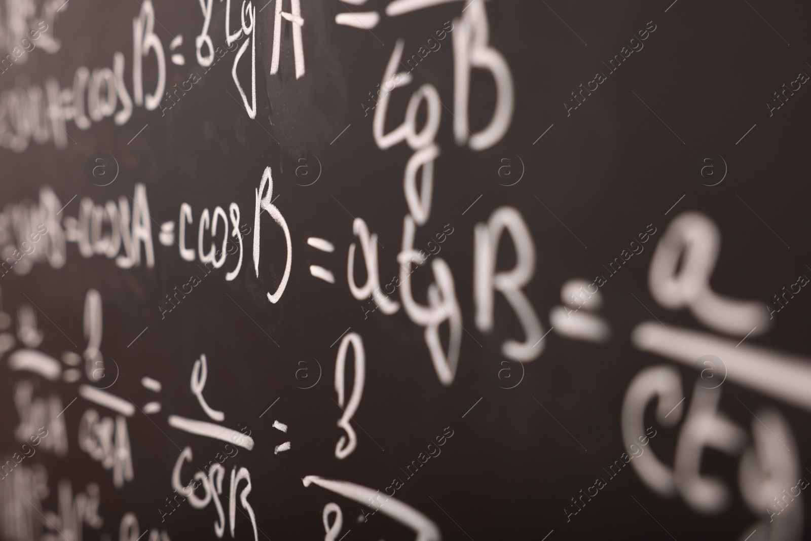 Photo of Different mathematical formulas written with chalk on blackboard, closeup