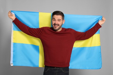 Man with flag of Sweden on light grey background