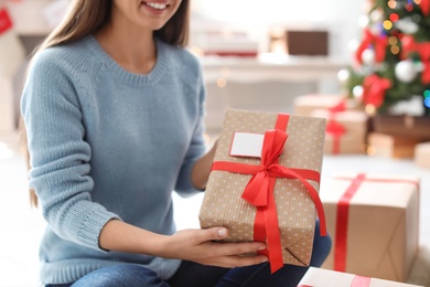 Photo of Young woman with Christmas gift at home