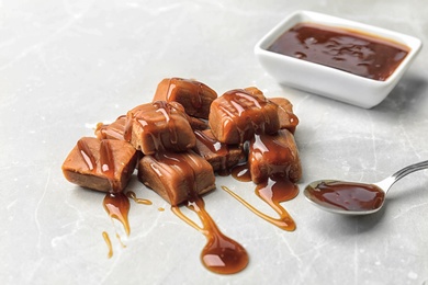 Photo of Delicious candies with caramel sauce on light background