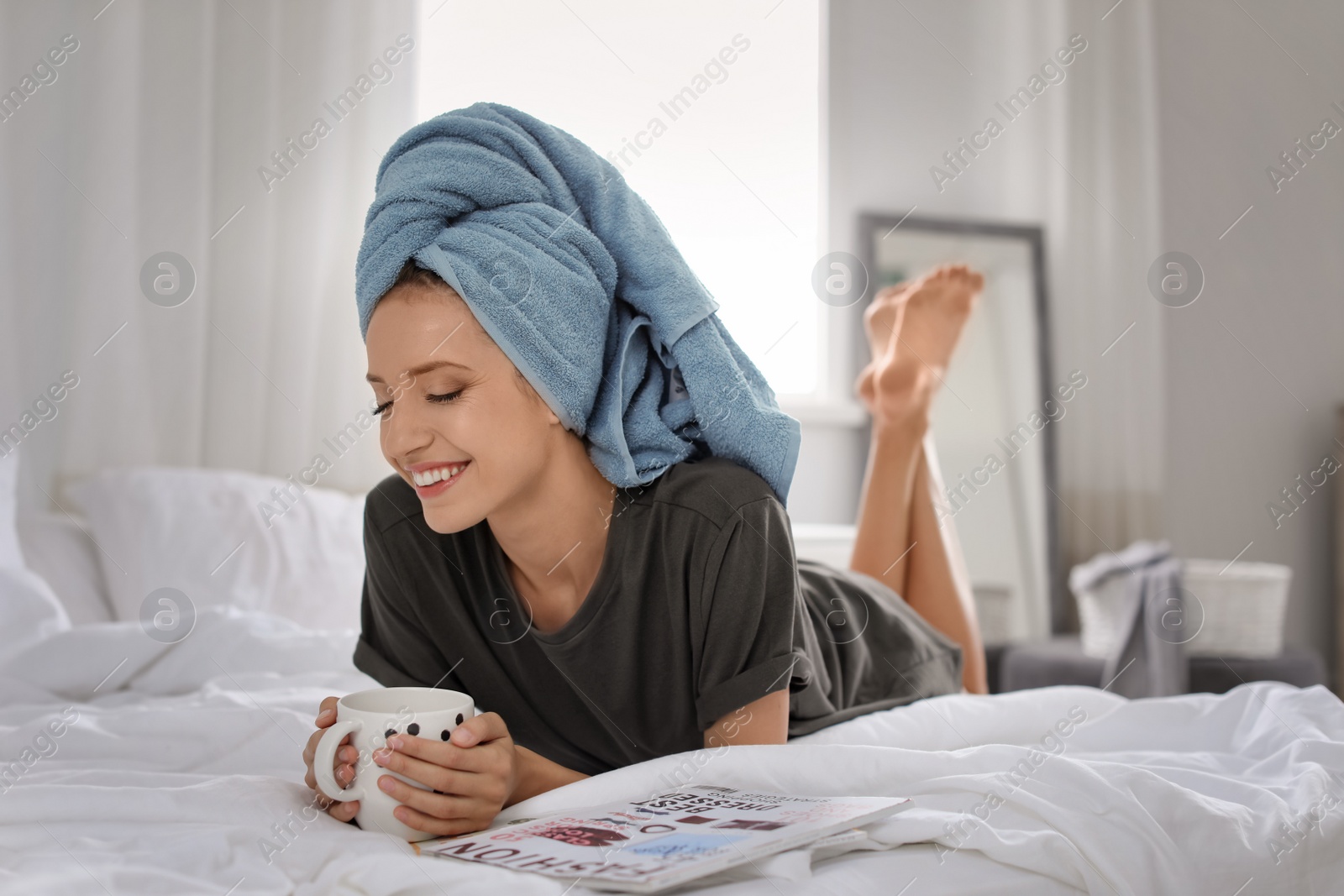 Photo of Young happy woman with aromatic coffee lying on bed at home. Lazy morning