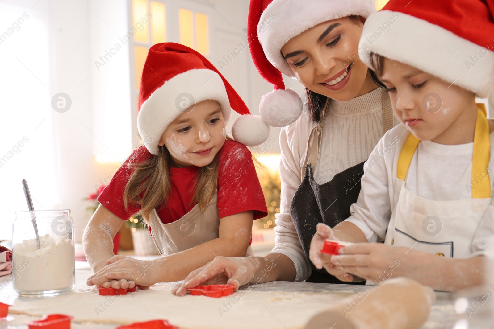 Photo of Mother and her cute little children making Christmas cookies in kitchen