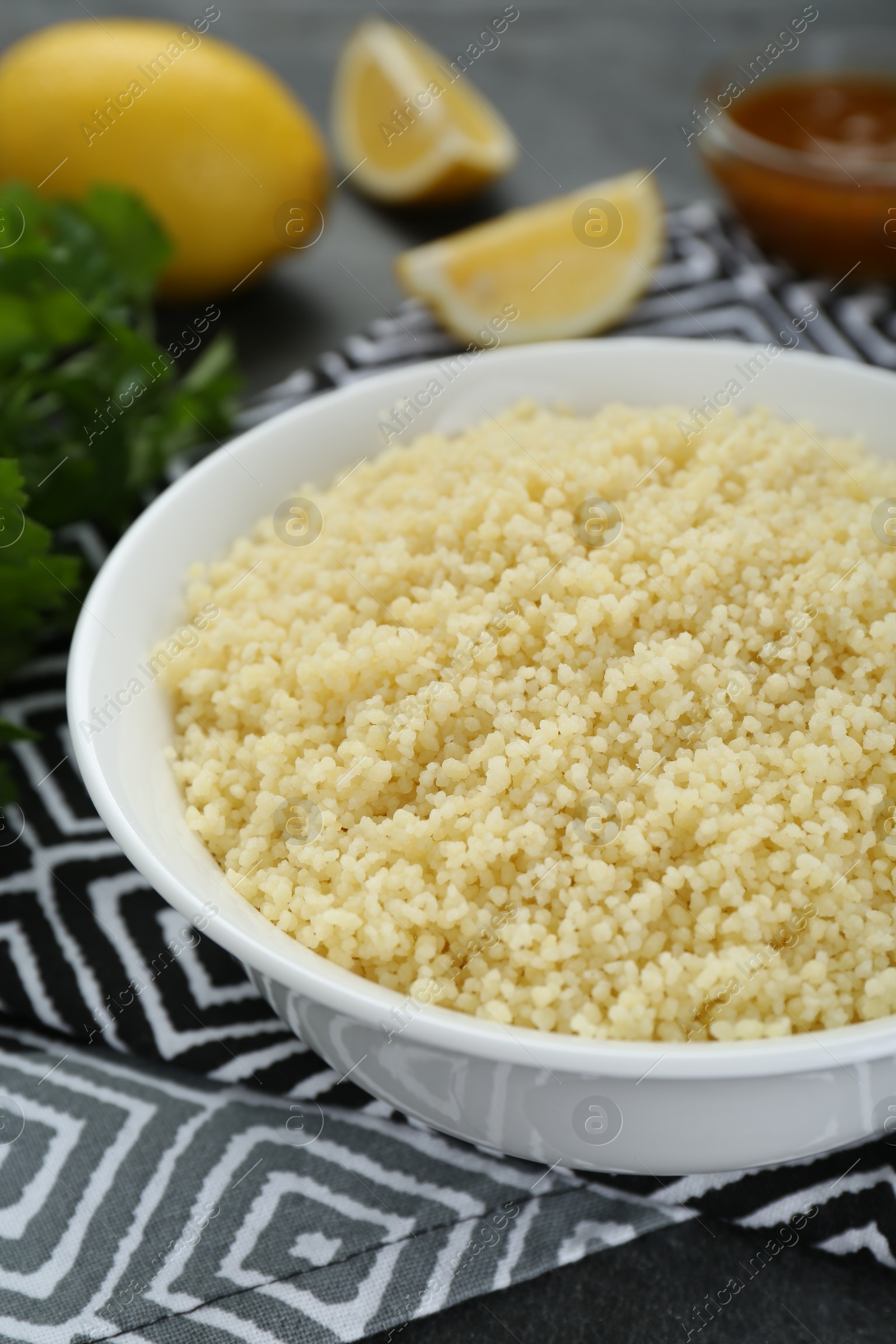 Photo of Bowl of tasty couscous on grey table, closeup