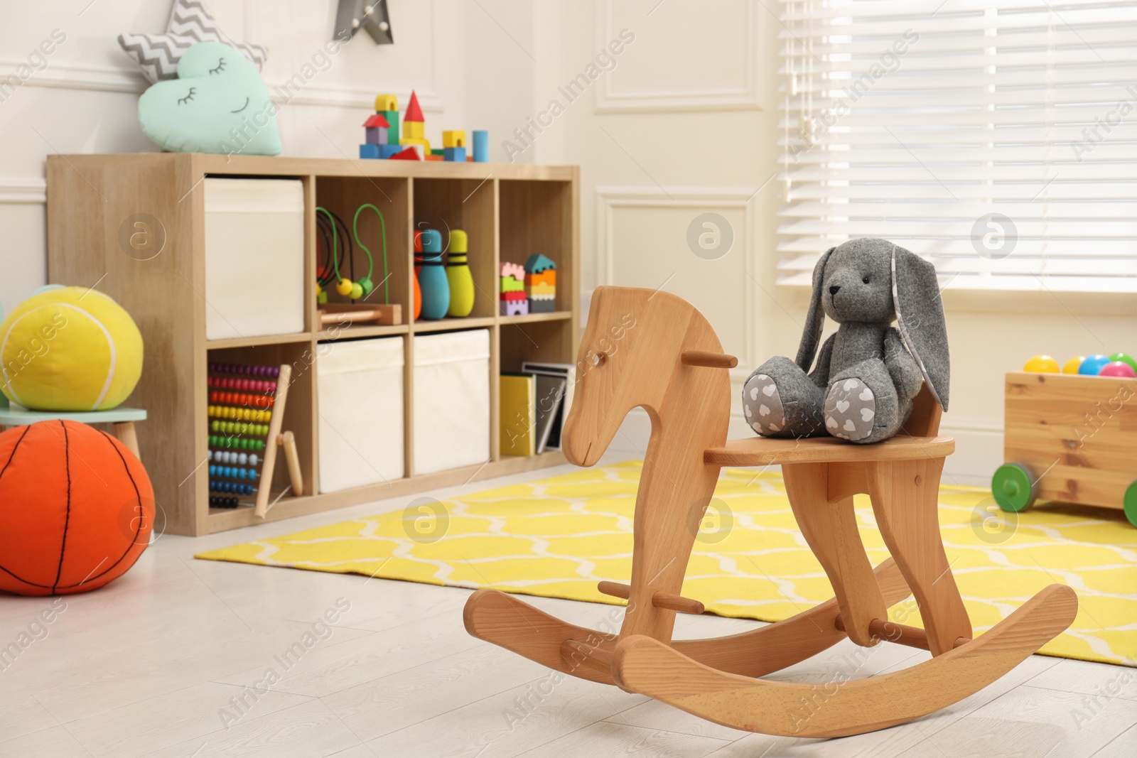 Photo of Stylish child's room interior with cute wooden rocking horse and toys