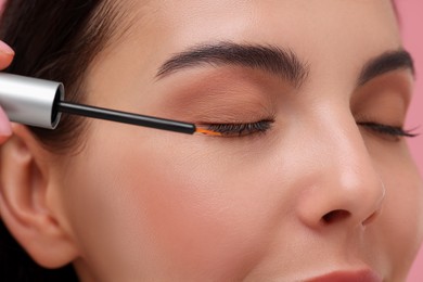 Photo of Woman applying serum onto her eyelashes, closeup. Cosmetic product
