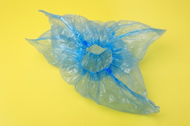 Photo of Pair of blue medical shoe covers on yellow background, closeup
