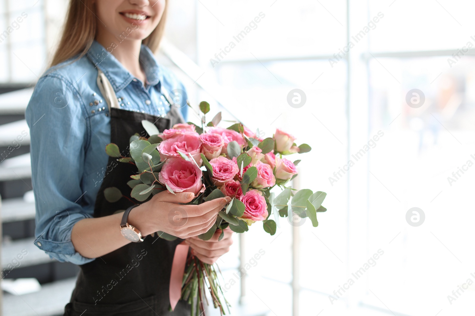Photo of Female florist holding bouquet of beautiful flowers, indoors