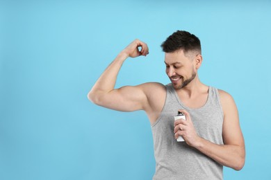 Photo of Handsome man applying deodorant on turquoise background. Space for text