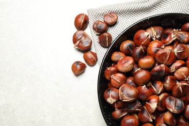 Photo of Delicious roasted edible chestnuts on light grey table, flat lay. Space for text