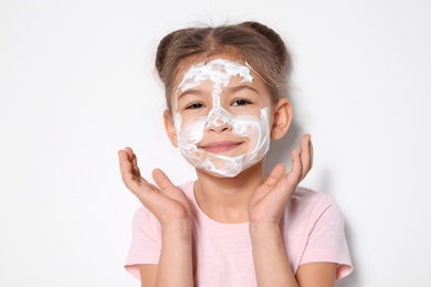 Photo of Cute little girl with soap foam on face against white background