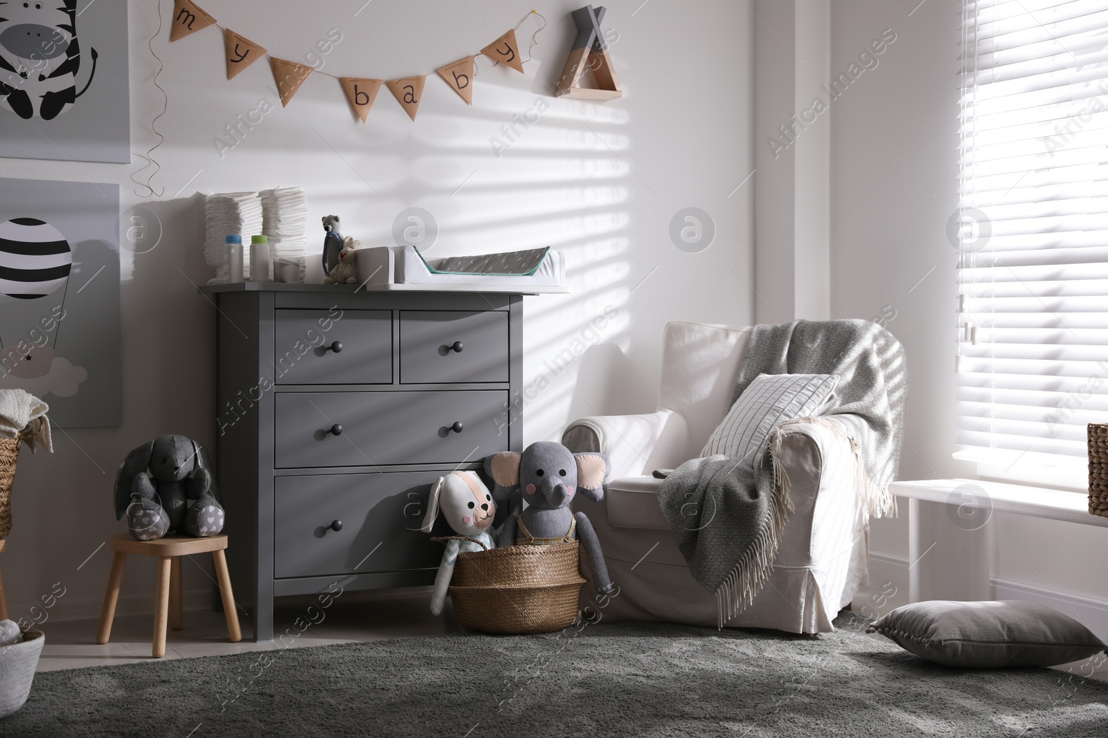 Photo of Chest of drawers with changing tray and pad in baby room. Interior design