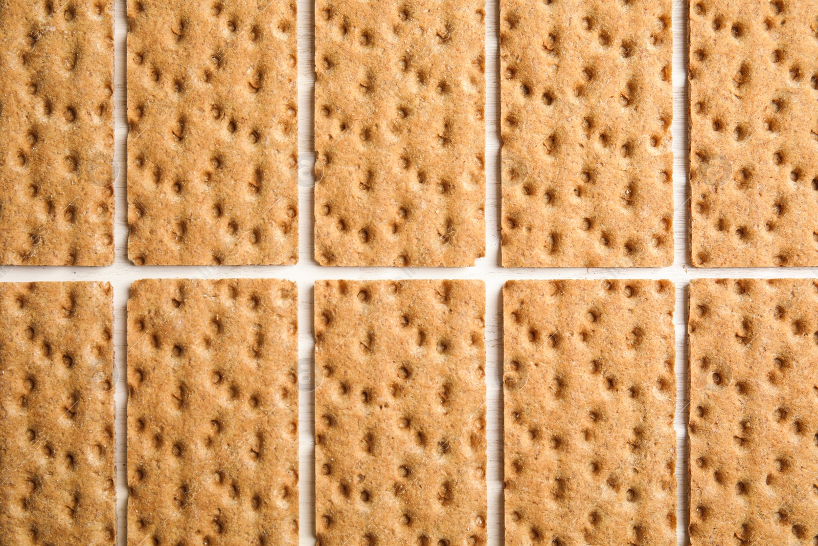 Photo of Fresh rye crispbreads on white wooden table, flat lay