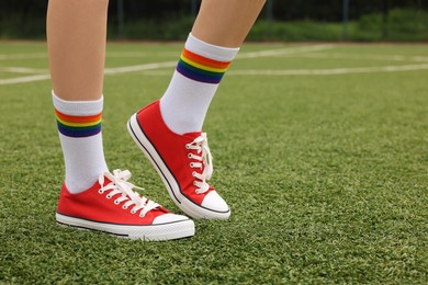 Photo of Woman wearing red classic old school sneakers on green court outdoors, closeup. Space for text
