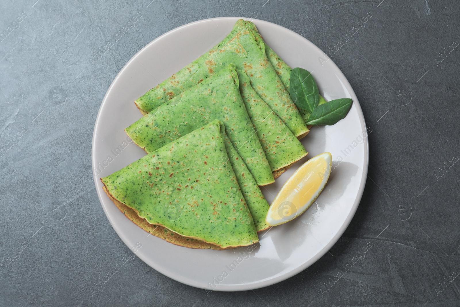 Photo of Tasty spinach crepes served on grey table, top view