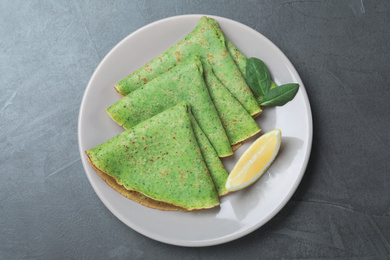 Tasty spinach crepes served on grey table, top view