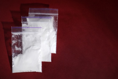 Cocaine in plastic bags on color background, top view. Space for text