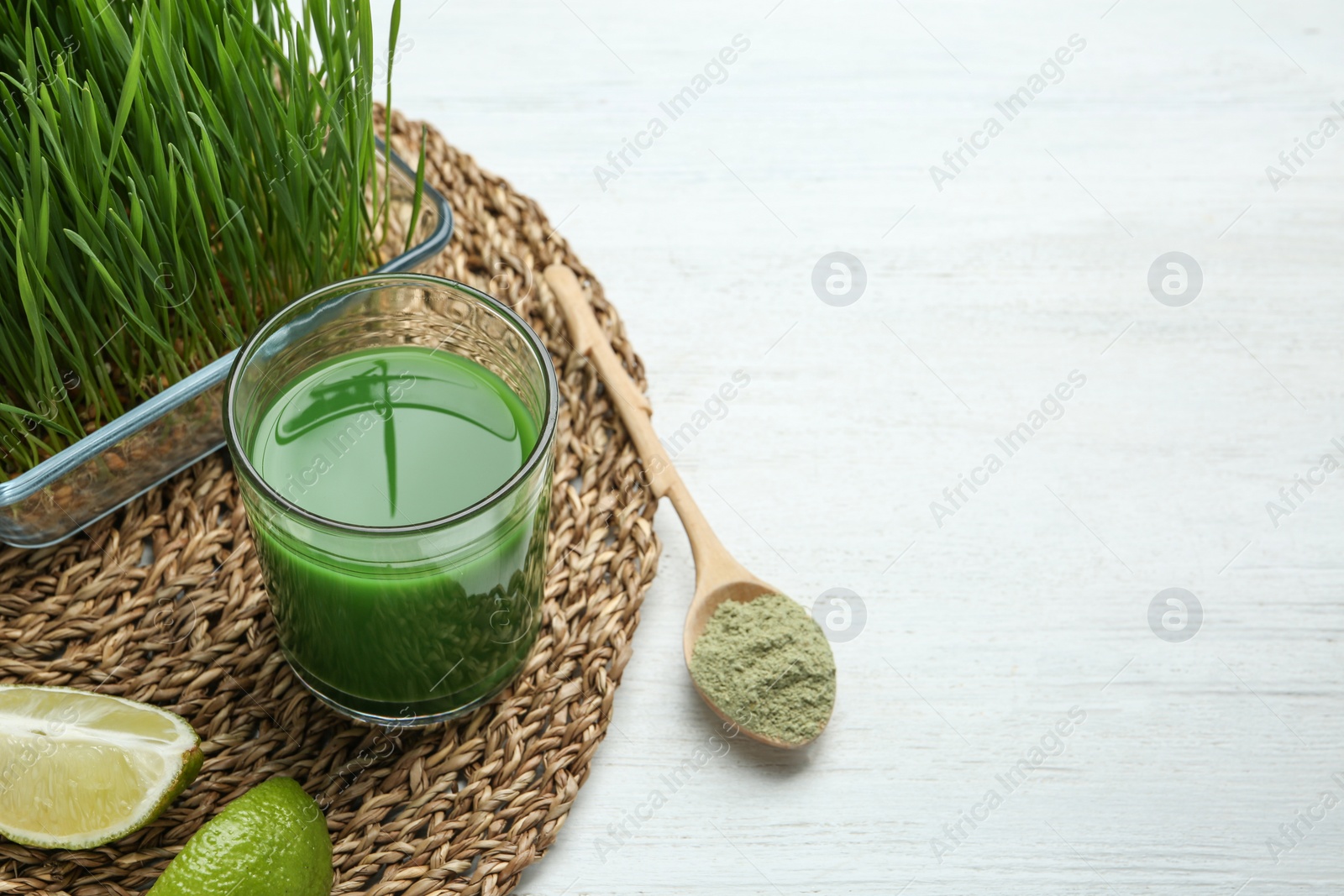 Composition with glass of wheat grass juice and lime on white wooden table. Space for text Photo of Composition with glass of wheat grass juice and lime on white wooden table. Space for text