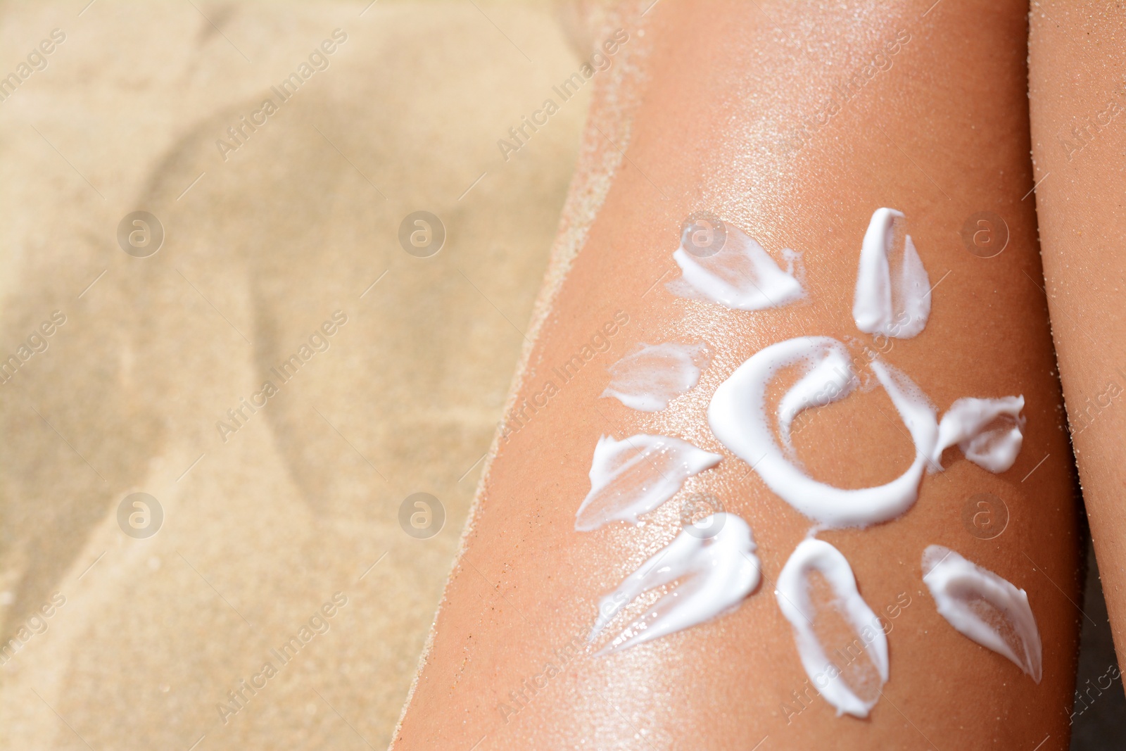 Photo of Sun drawn with sunscreen on woman's leg at beach, closeup. Space for text