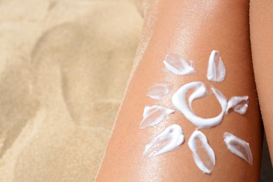 Sun drawn with sunscreen on woman's leg at beach, closeup. Space for text