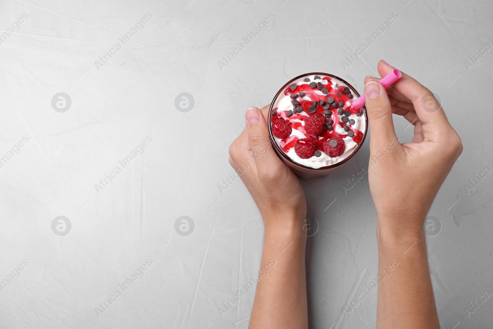 Photo of Woman with tasty milk shake at light grey table, top view. Space for text
