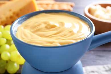 Pot of tasty cheese fondue and products on table, closeup