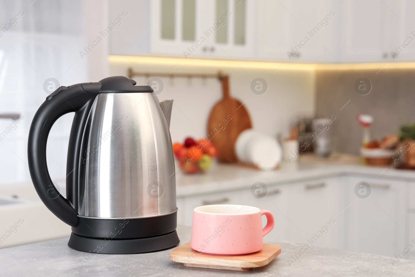 Photo of Electric kettle and cup on table in kitchen. Space for text