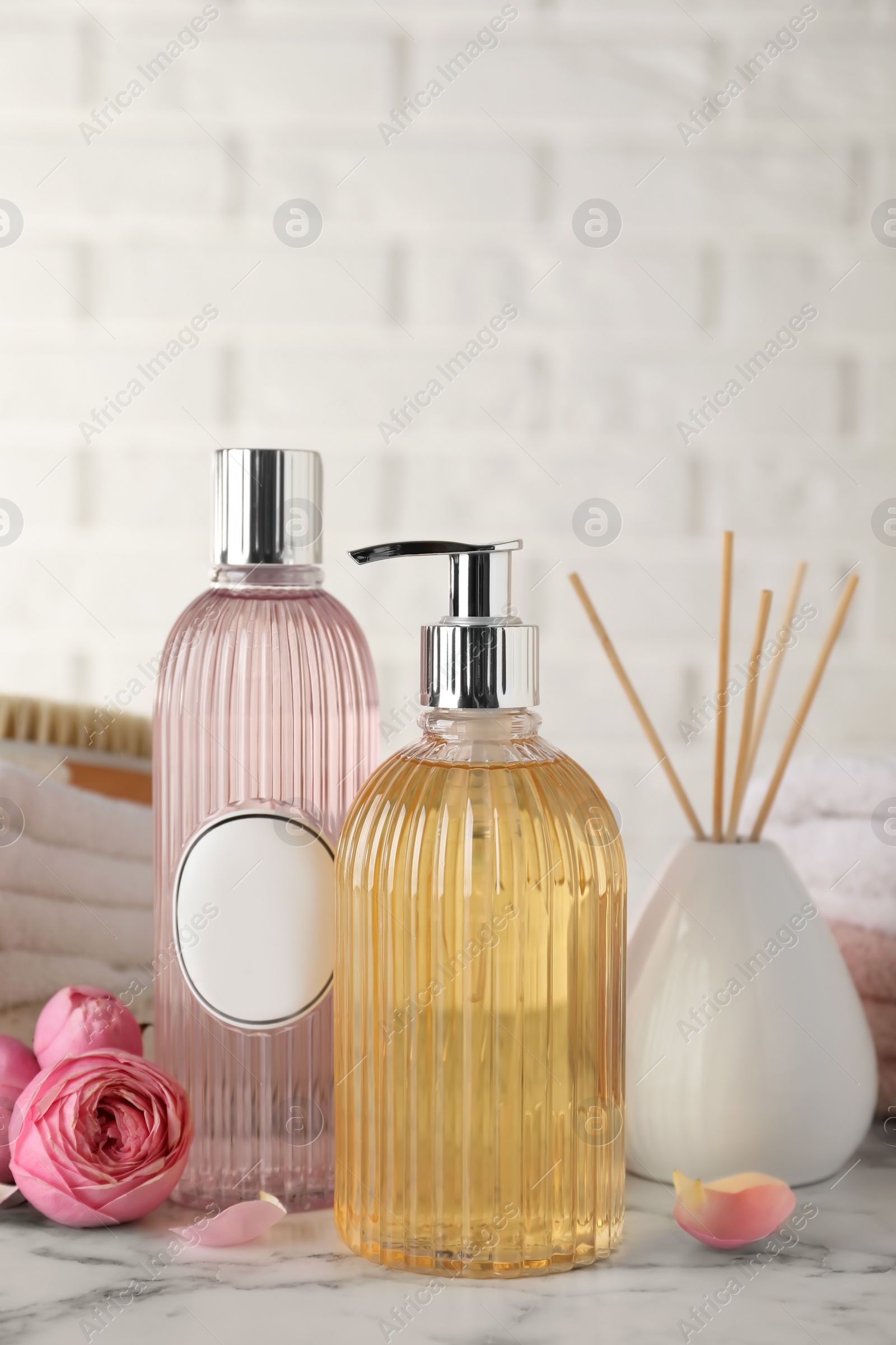 Photo of Stylish dispenser with liquid soap and other bathroom amenities on white marble table