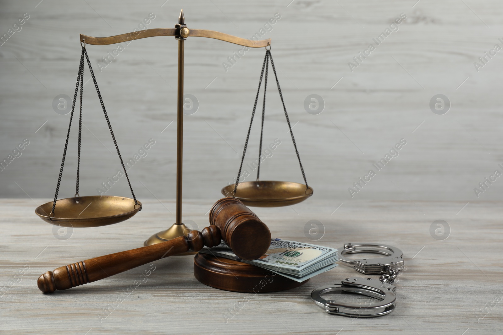 Photo of Judge's gavel, money and scales of justice on wooden table. Space for text