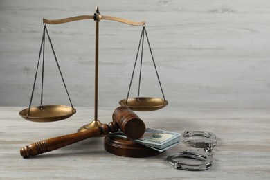 Judge's gavel, money and scales of justice on wooden table. Space for text