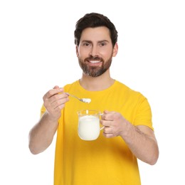 Photo of Handsome man with delicious yogurt and spoon on white background