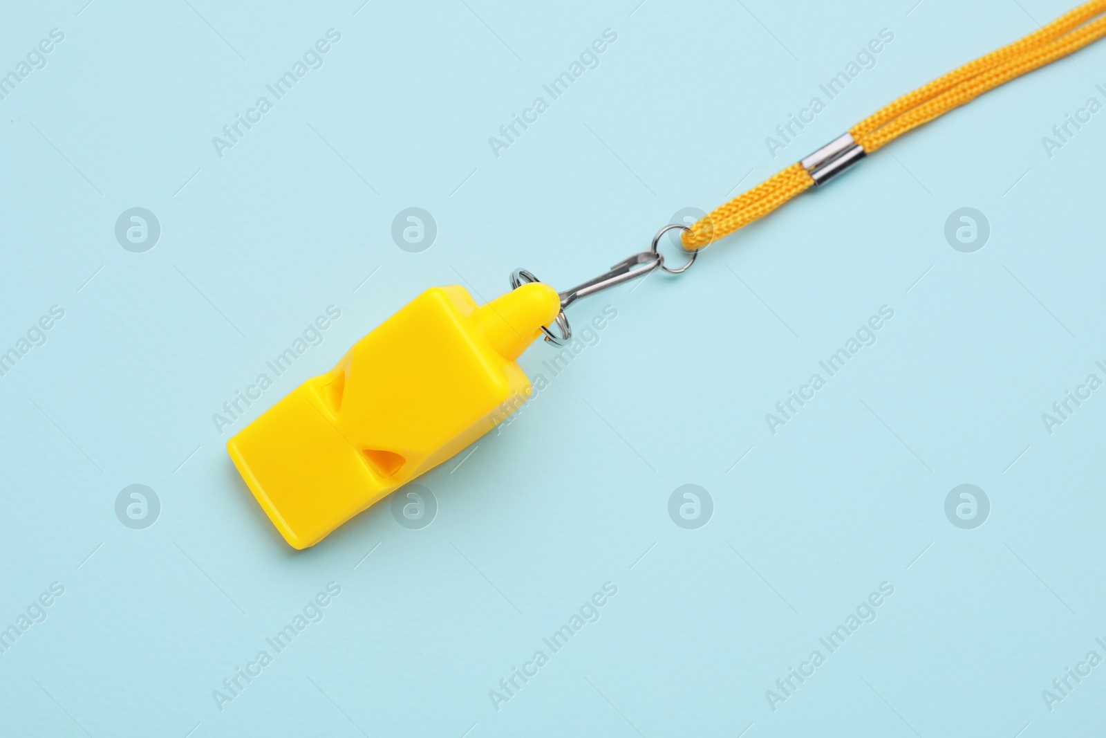 Photo of One yellow whistle with cord on light blue background, top view
