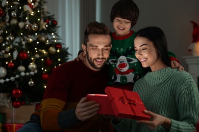 Happy family opening gift box with magical light at home. Christmas celebration