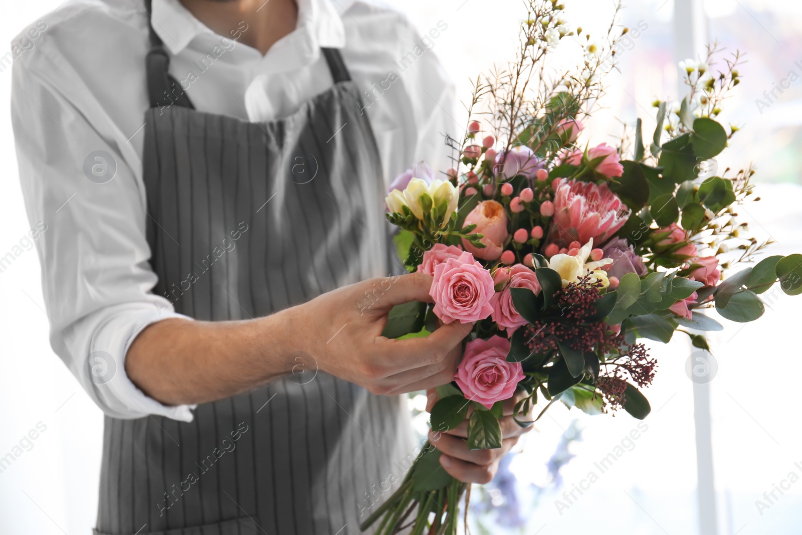Photo of Male florist creating beautiful bouquet, closeup