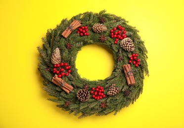 Beautiful Christmas wreath on yellow background, top view