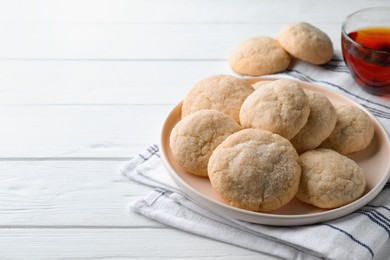 Delicious sugar cookies and cup of tea on white wooden table, space for text