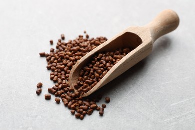 Photo of Scoop with buckwheat tea granules on light grey table, closeup