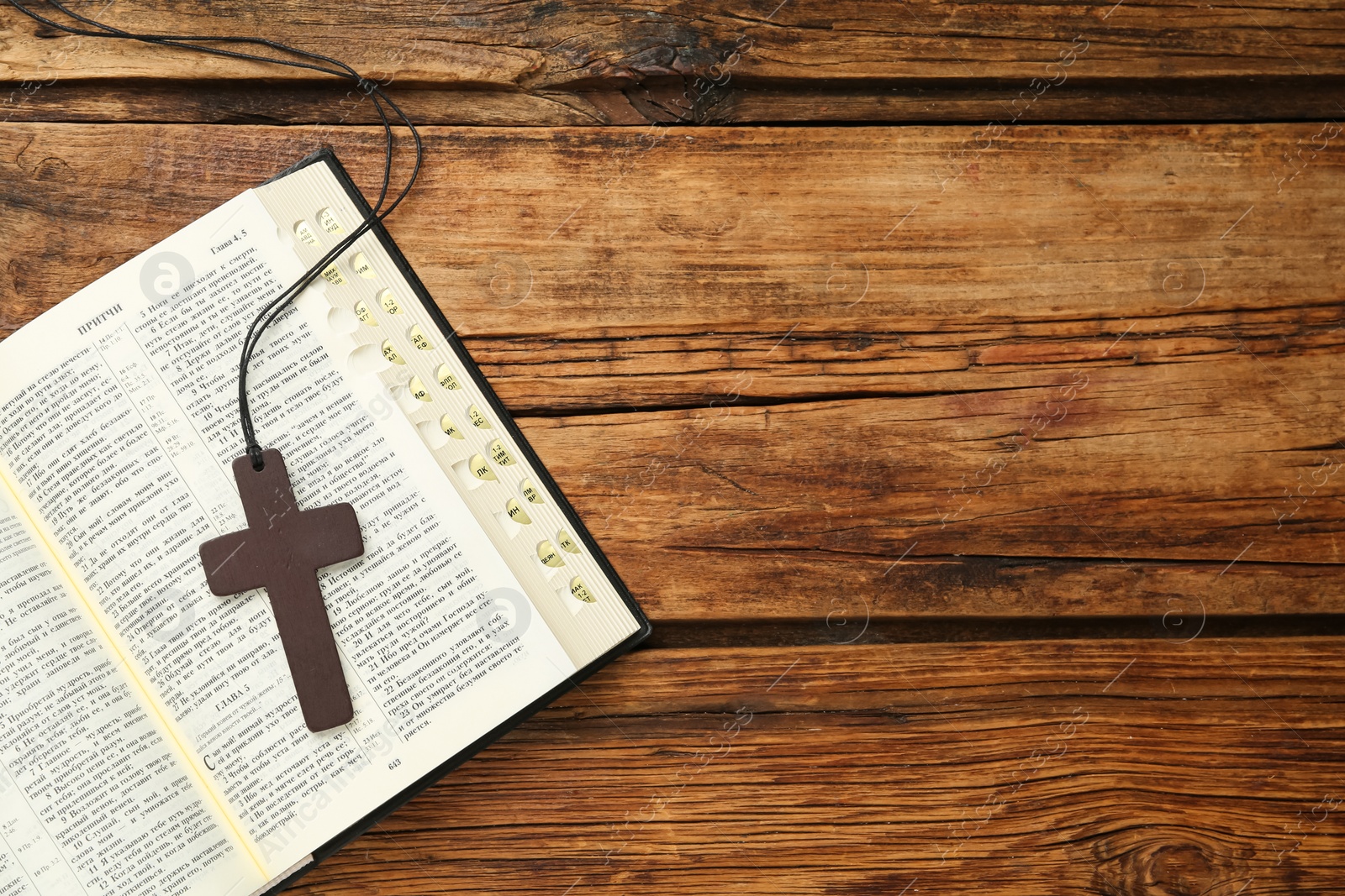 Photo of MYKOLAIV, UKRAINE - DECEMBER 20, 2021: Christian cross and Bible on wooden table, top view. Space for text