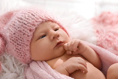 Photo of Cute newborn baby in hat lying on fuzzy blanket, closeup