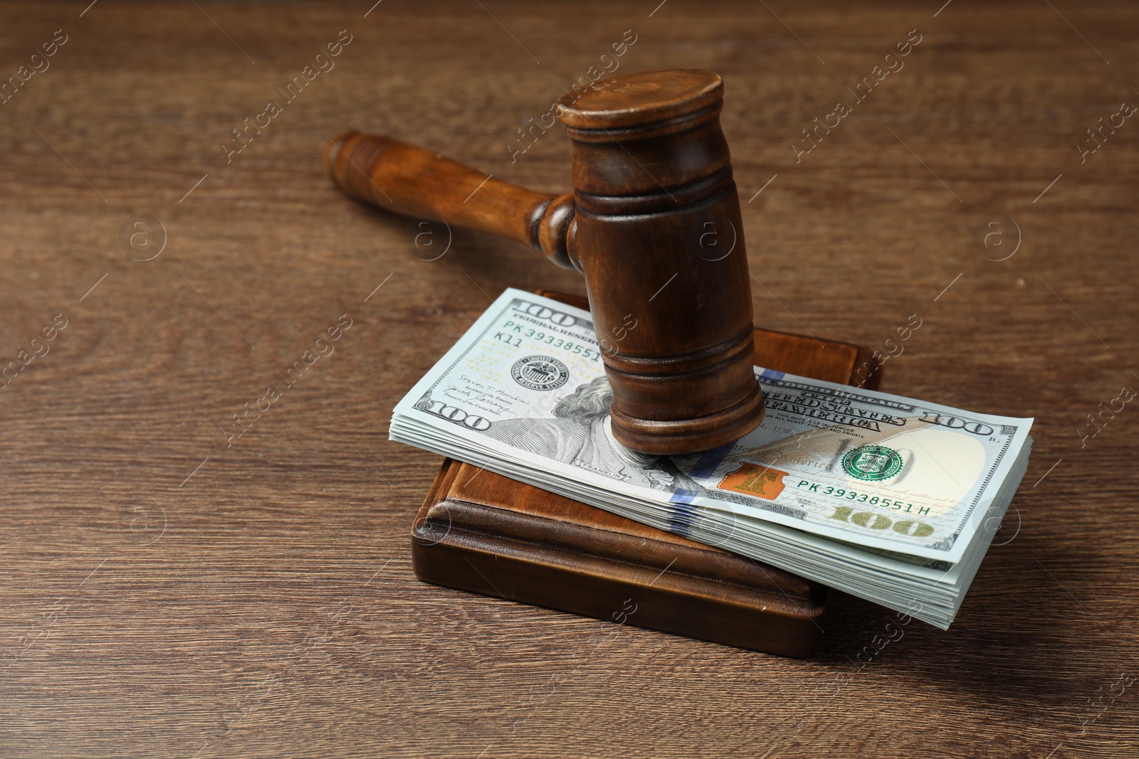 Photo of Law gavel with stack of dollars on wooden table, closeup. Space for text