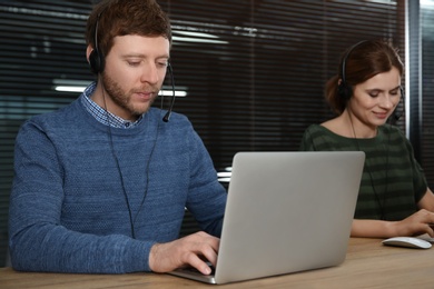 Photo of Team of technical support with headsets at workplace