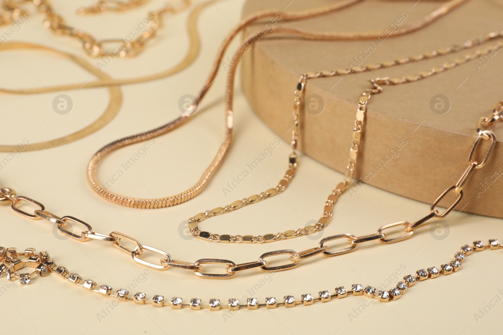 Photo of Different metal chains on beige background, closeup. Luxury jewelry
