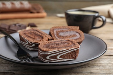 Tasty chocolate cake roll with cream on wooden table, closeup