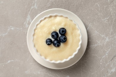 Photo of Delicious semolina pudding with blueberries on marble table, top view