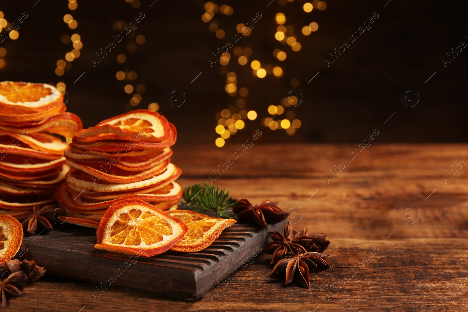 Photo of Dry orange slices and anise stars on wooden table, space for text. Bokeh effect