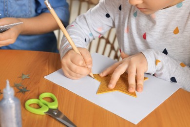 Photo of Cute little children making beautiful Christmas greeting card at wooden table, closeup
